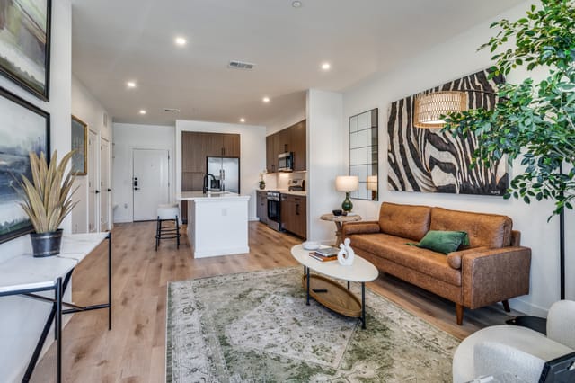 Open-concept living area and kitchen with quartz countertops and wood-style flooring at The Marcus